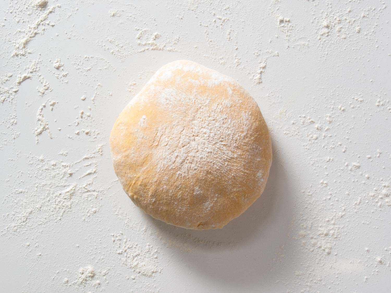 Dough for pumpkin yeast sandwich bread after proofing and before shaping, sitting on a floured countertop.