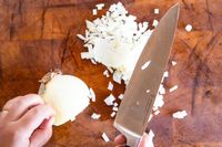 Chopped onion on a cutting board with a Wüsthof knife