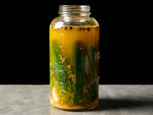 A large glass jar full of lacto-fermented dill pickles.