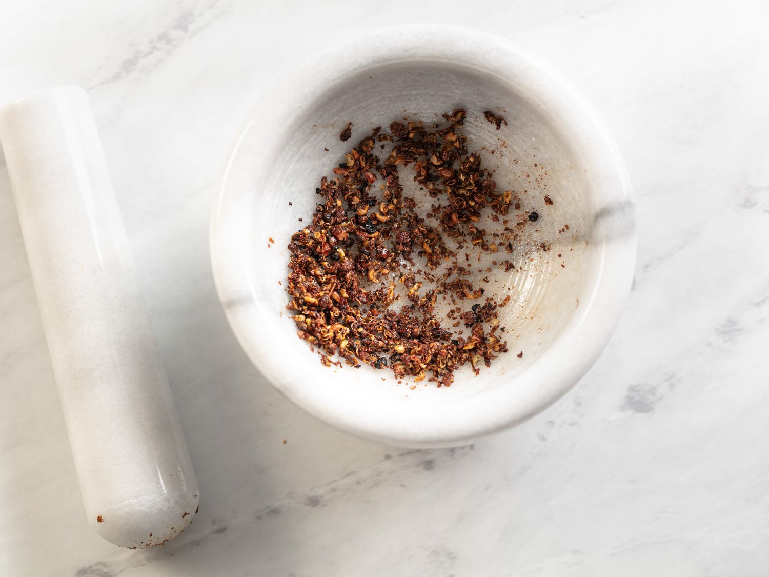 Coarsely ground Sichuan peppercorns in a pestle and mortar for mapo tofu.