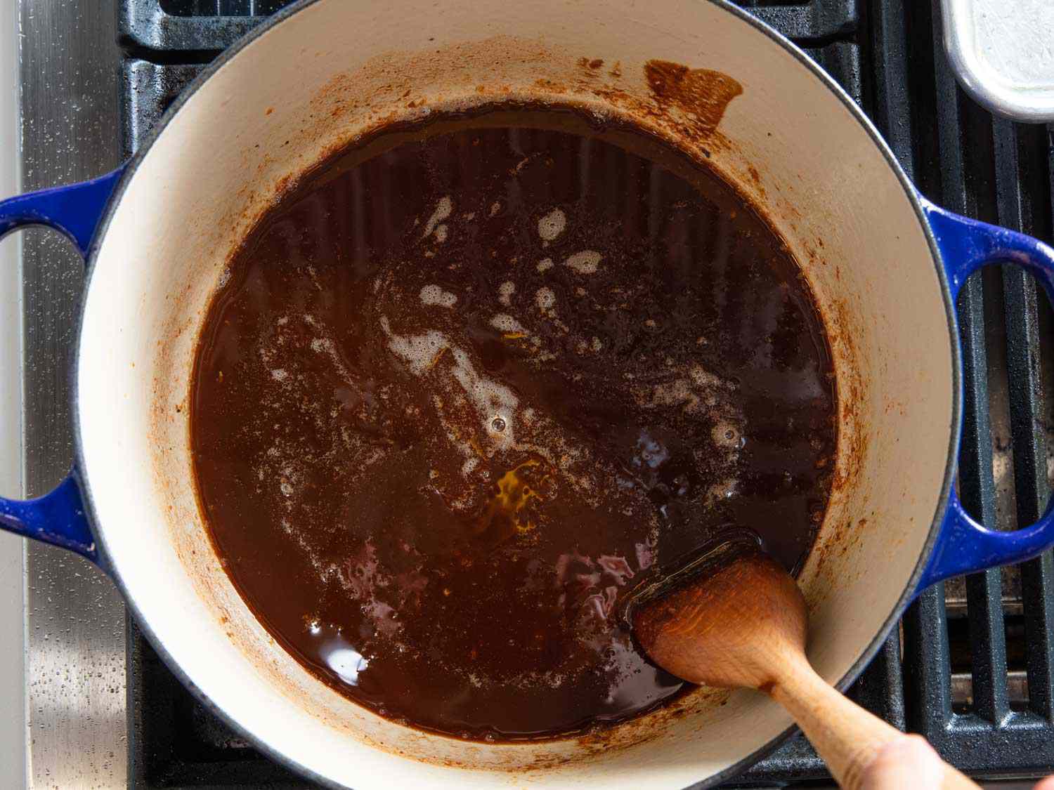 A roux in a Dutch oven being stirred with a wooden spoon.