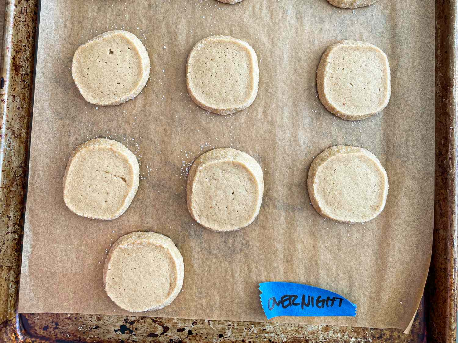 Tray of cookie dough rounds on parchment paper labeled overnight with a blue tag