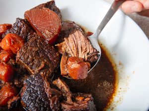 Spoon lifting beef chunks and vegetables from a bowl of stew