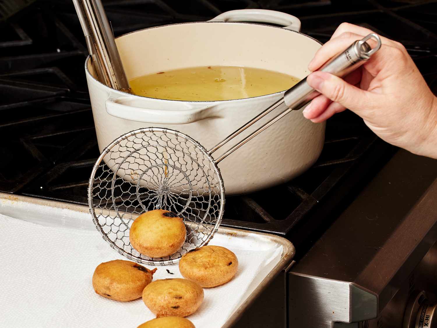 Oreos deep fried, being placed from oil onto paper towel lined sheet pan 