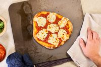 A cooked pizza on a pizza steel.