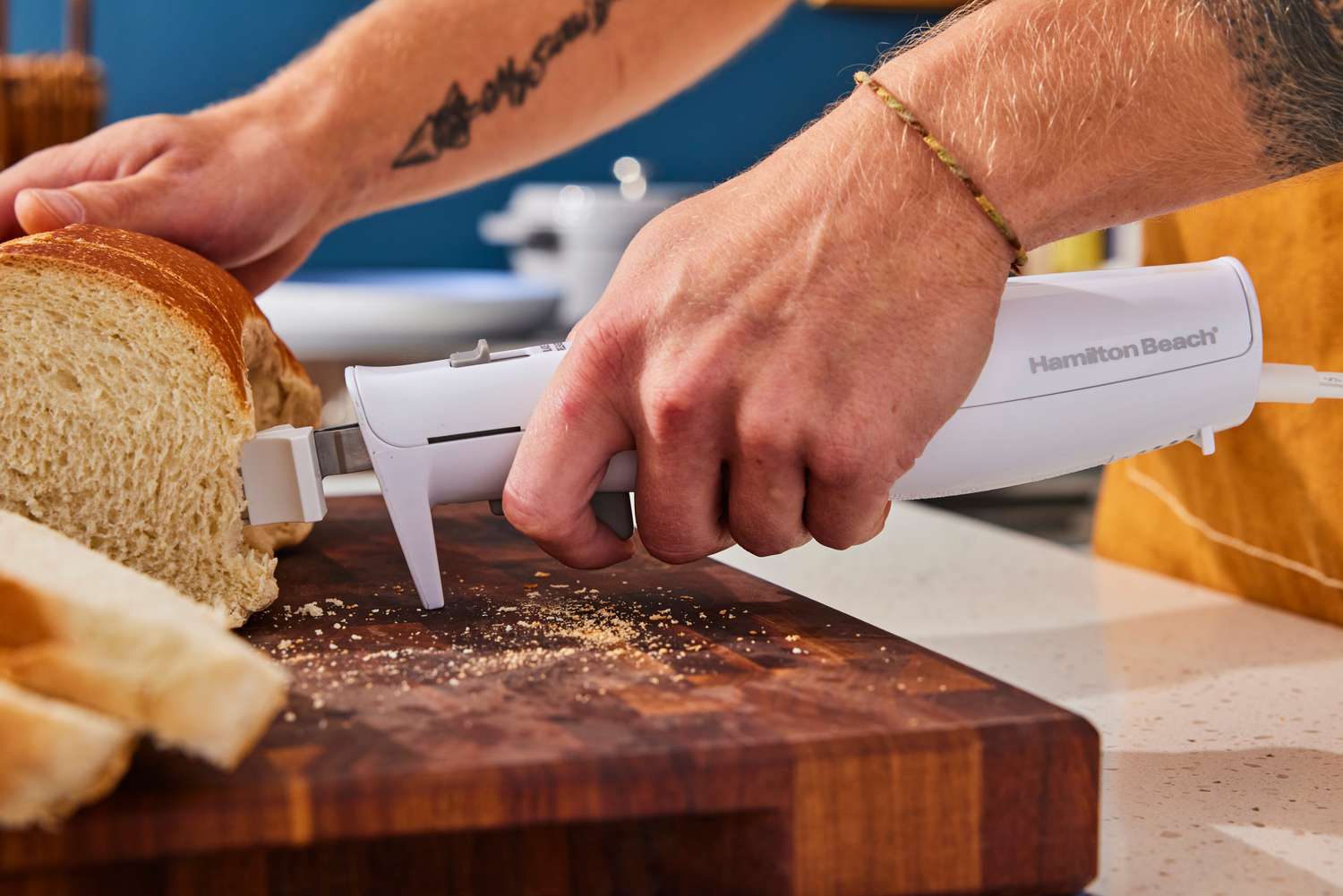 a person holding the hamilton beach electric knife and cutting bread