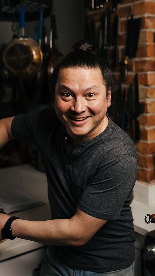 Portrait of J. Kenji Lopez Alt, looking directly at the camera while smiling, in his kitchen.