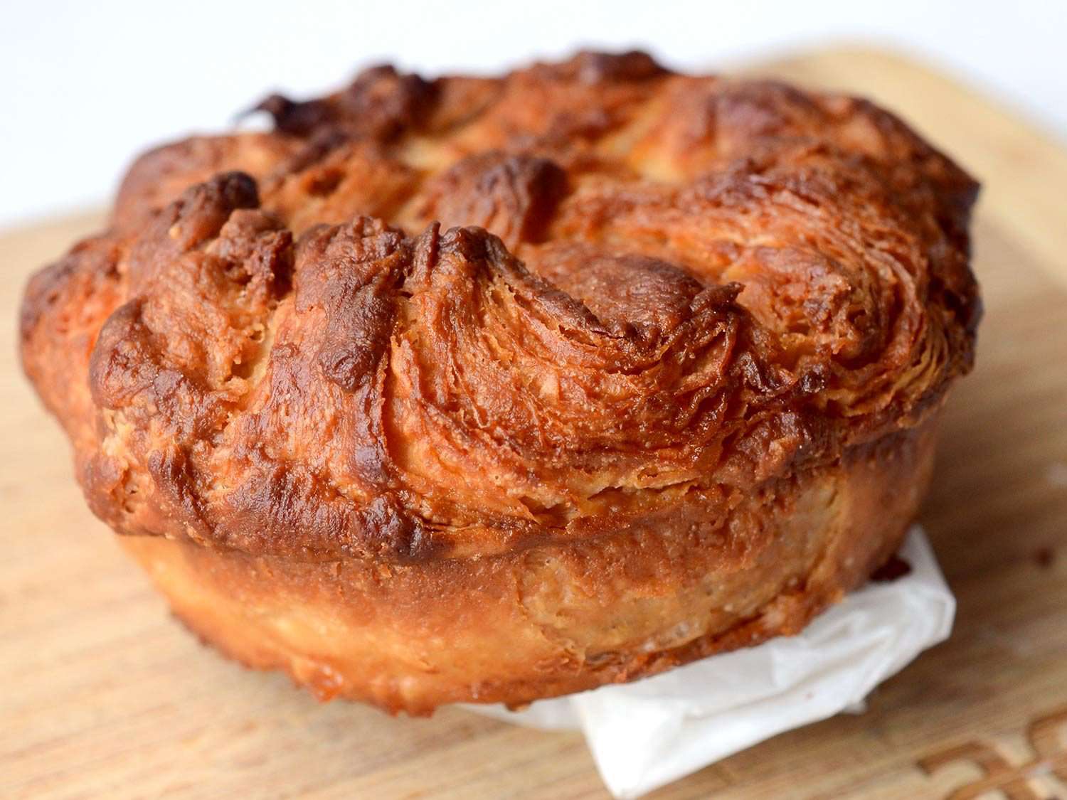 Close up photo of kouign amann propped up on white paper bag.