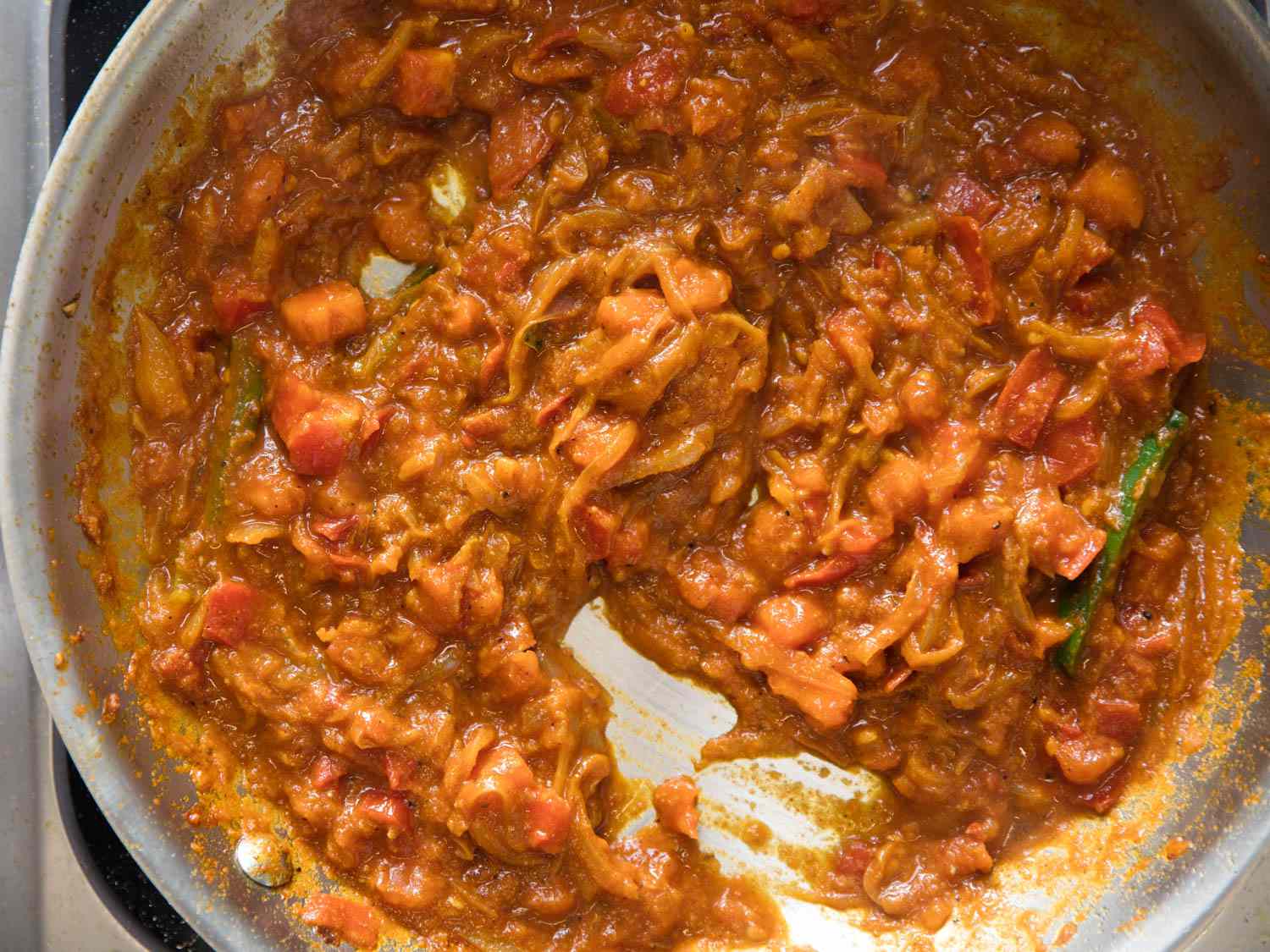 The tomato and onion bhuna curry in a stainless steel pan.