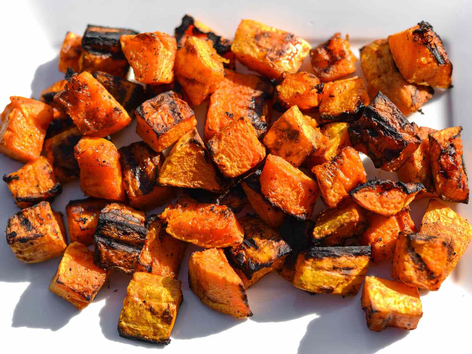 Grilled butternut squash cubes with nice charring marks on a serving plate. 