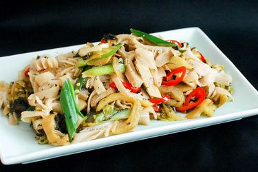 Stir-fried tripe with pickled mustard greens and fermented black beans, served on a square serving platter.
