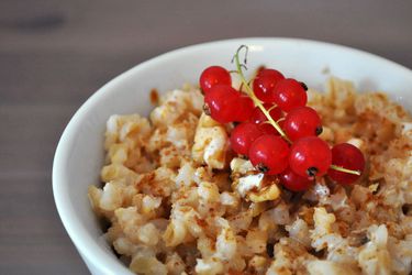 A bowl of barley porridge topped with red currants.