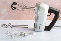 The Breville hand mixer on a white kitchen countertop.