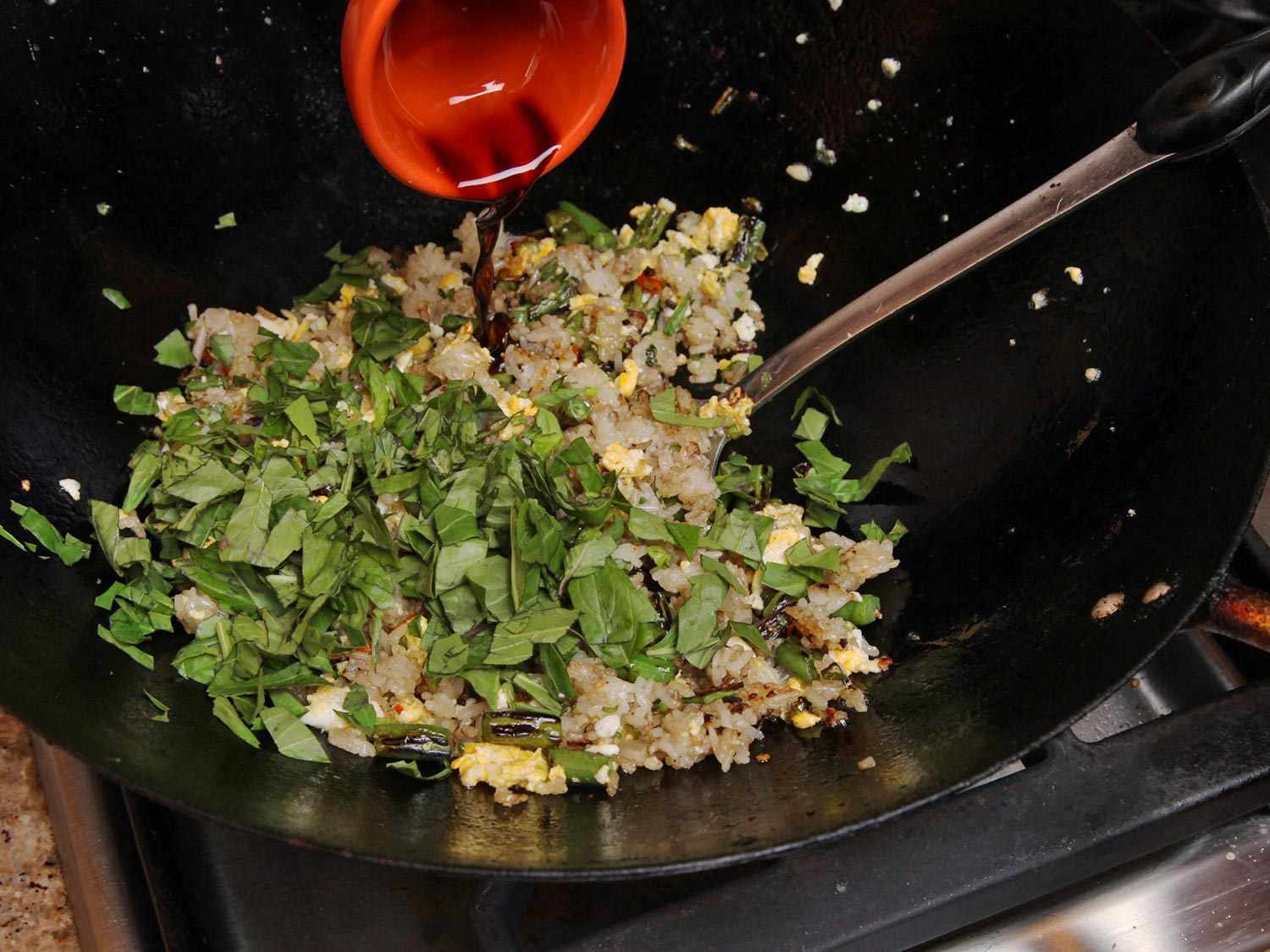 Basil, soy sauce, and fish sauce are added to the fried rice.