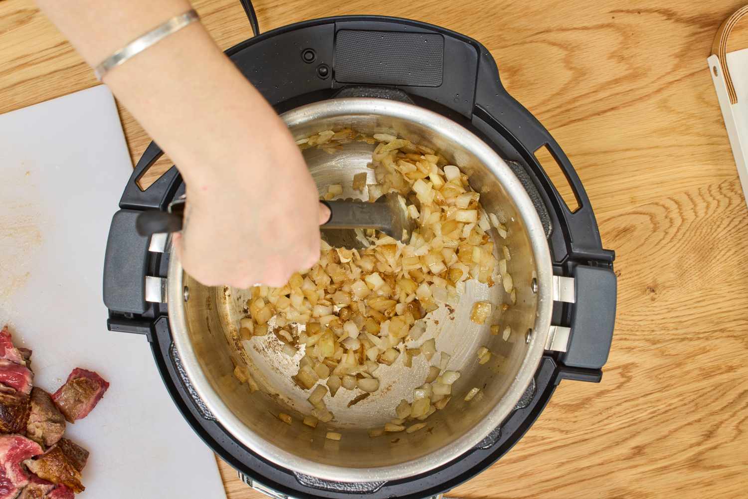 A person cooks onions in the Instant Pot Pro Plus Wi-Fi Smart 10-in-1 6-Quart Pressure Cooker