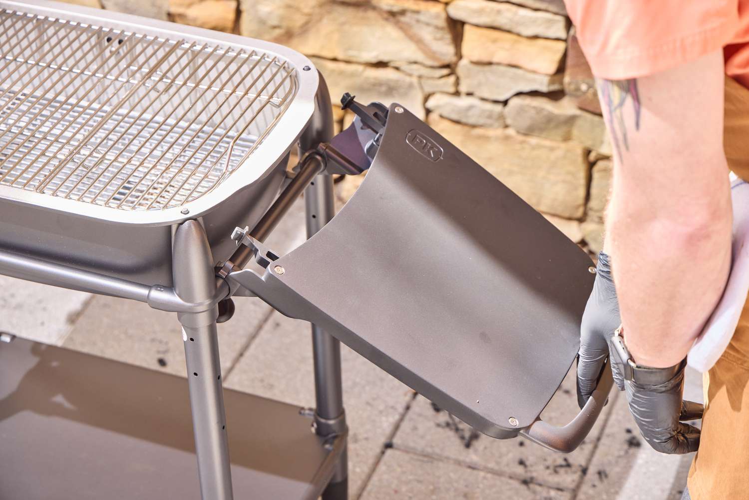 A person touching the side tray of the PK Grills Original PK300 Grill & Smoker 
