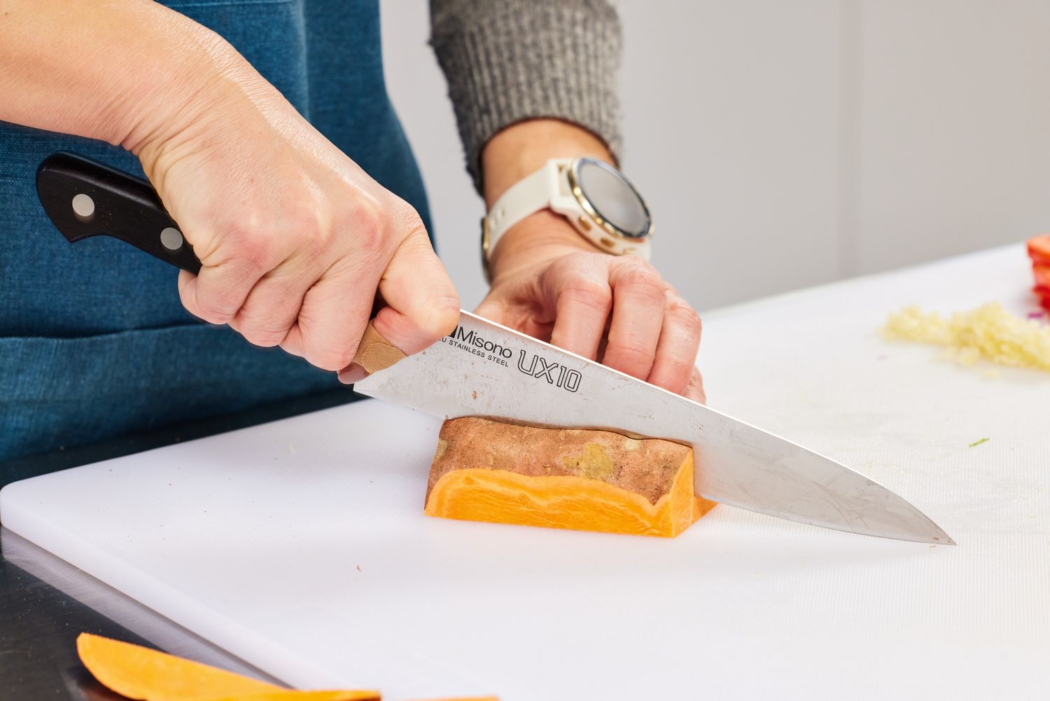 Hands slicing a sweet potato with a Misono UX10 8.2-Inch Gyutou