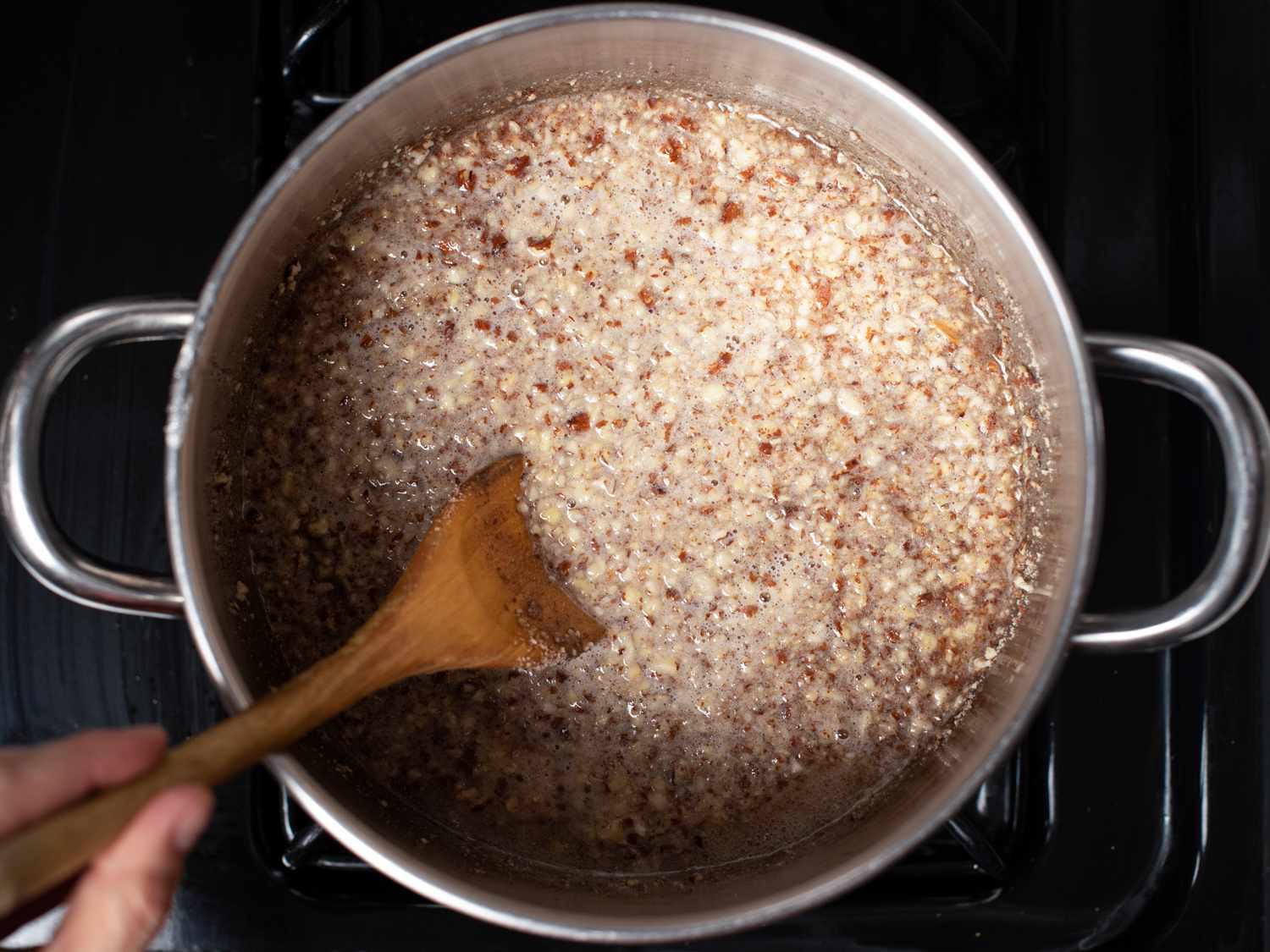 Toasted almonds added to syrup in a pan. 