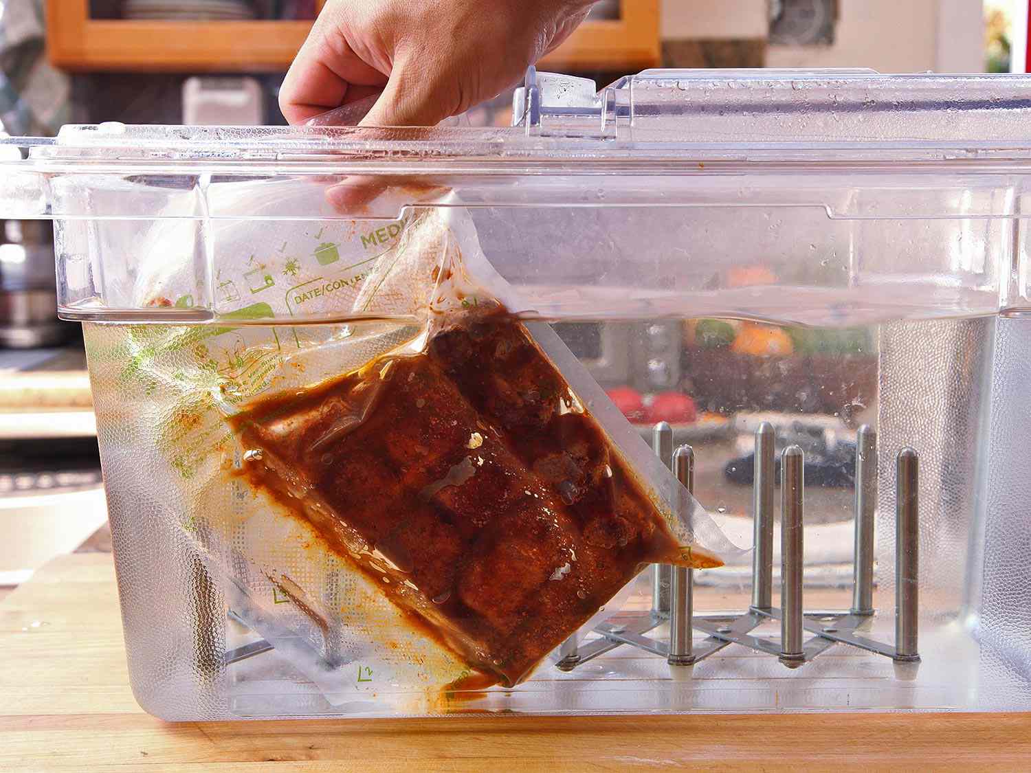 Dropping a vac-sealed bag of ribs and rub into a tub of water to sous-vide.