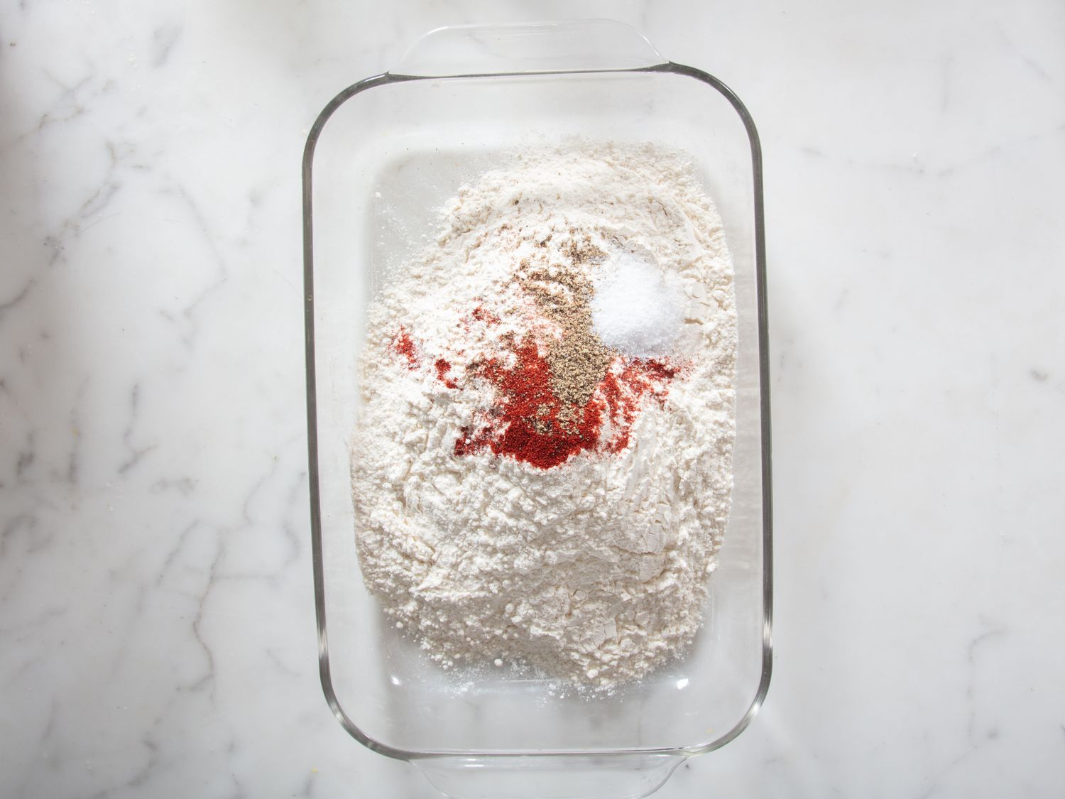 A mixture of dry ingredients including flour and spices in a glass baking dish
