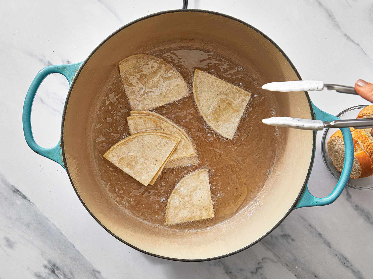 Making tortillas in a pot of oil with tongs