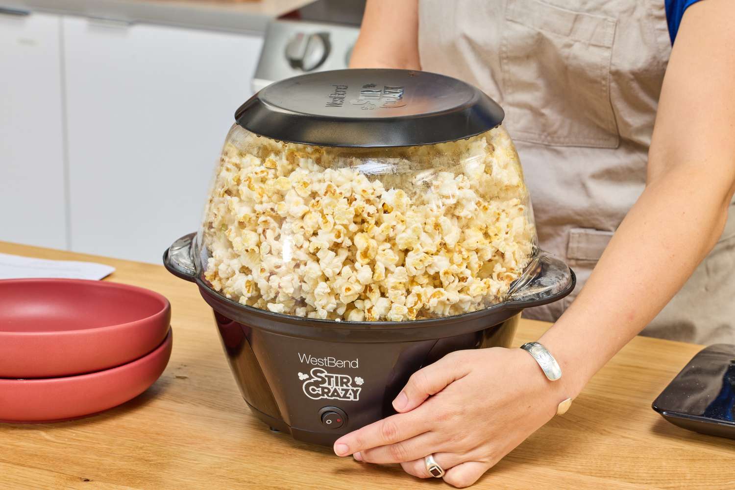 A person lifts up the West Bend Stir Crazy Electric Hot Oil Popcorn Popper