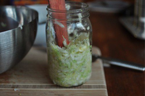 The salted cabbage is packed into the jar incrementally, lightly pounded down with a muddler or wooden spoon handle (?).