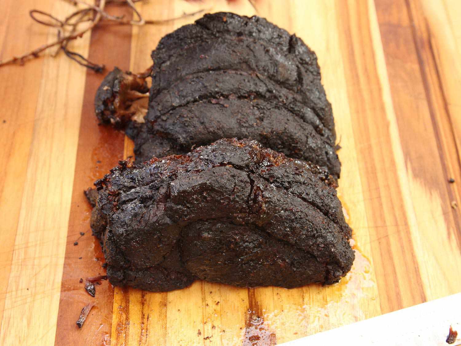 Barbecue smoked chuck roast, cut in half lengthwise and laid out cut side-down on a work surface.