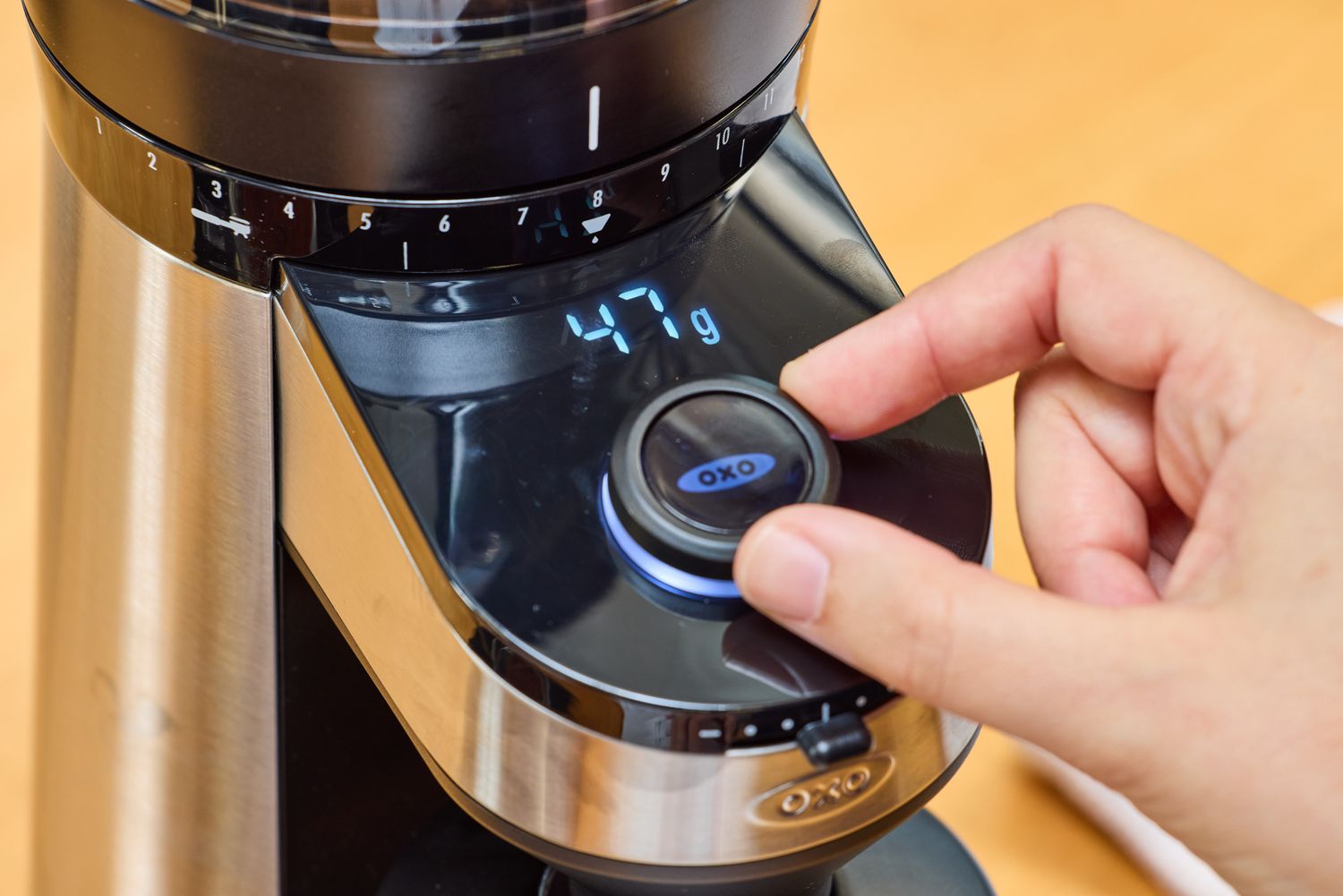 A person turns the dial on the OXO Brew Conical Burr Coffee Grinder With Integrated Scale