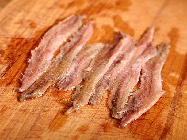 Rinsed anchovy fillets laid out on a cutting board.