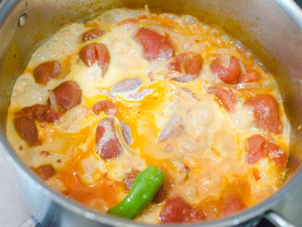 Adding cream to a pot of homemade butter chicken sauce