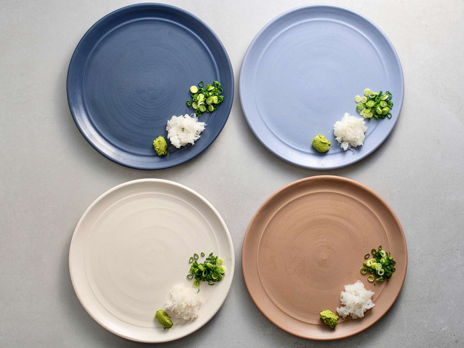 Four plates with wasabi, grated daikon, and scallions