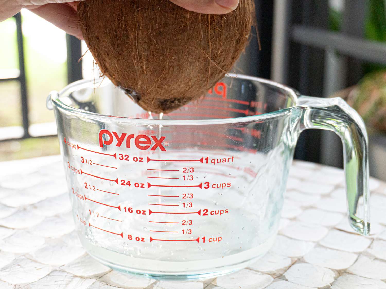 Side view of emptying coconut walk into a measuring cup