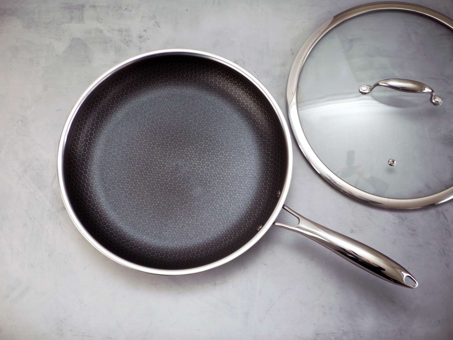 Hexclad pan with lid to the side on a gray surface