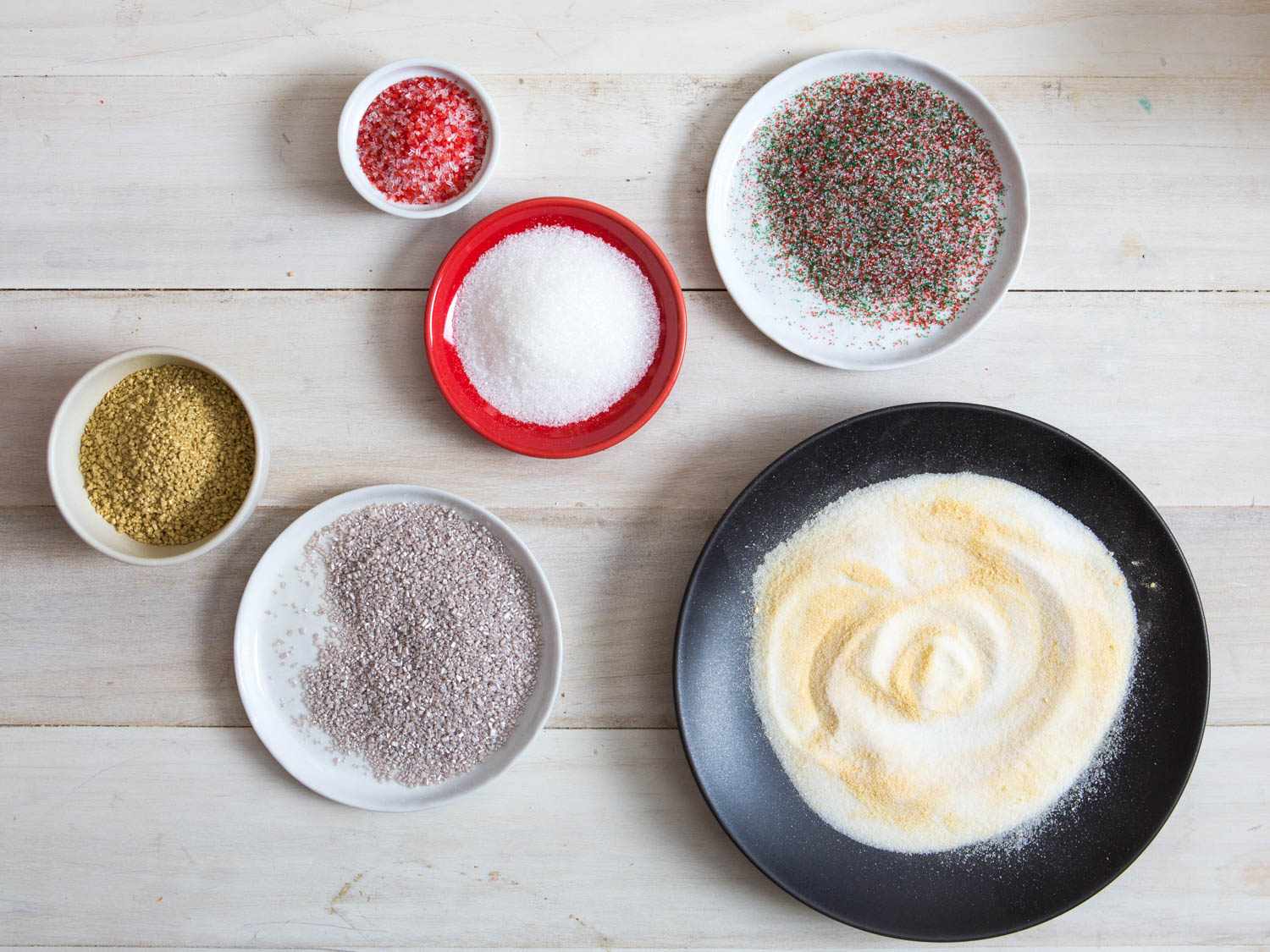 Overhead of various sugars and sprinkles for decorating soft sugar cookies.