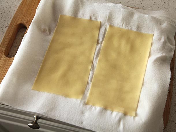 Two sheets of rehydrated dried pasta are arranged on a paper towel.
