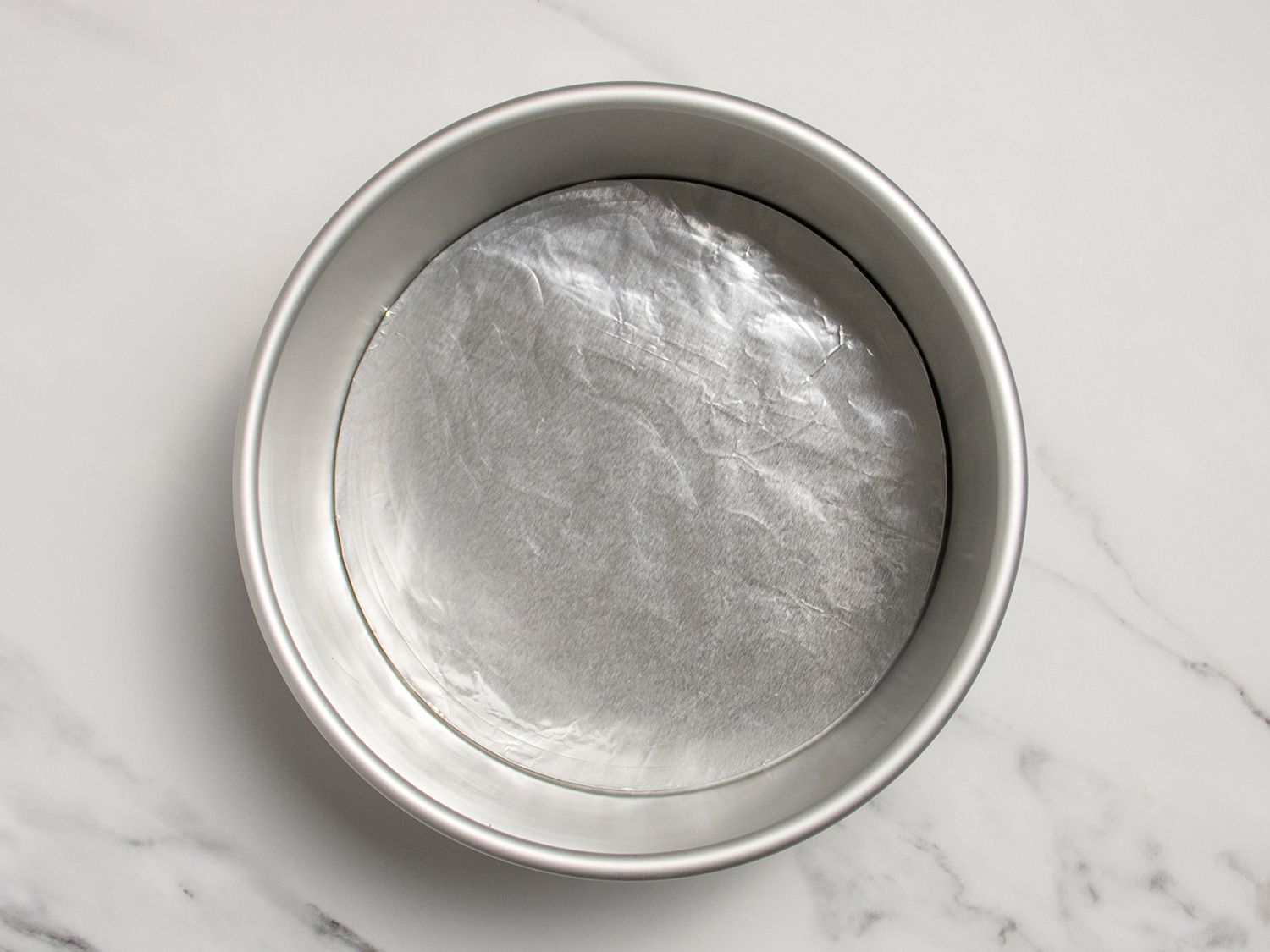 A cheesecake pan with the pan's removable bottom wrapped in aluminum foil.