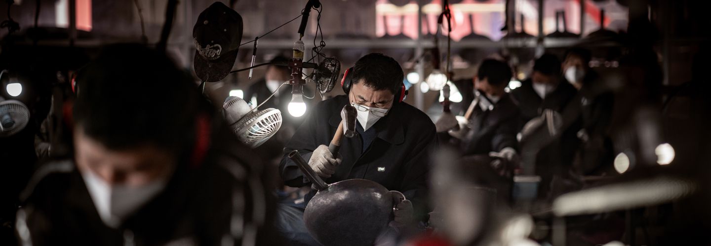 A wide view of a factory working working on a wok 