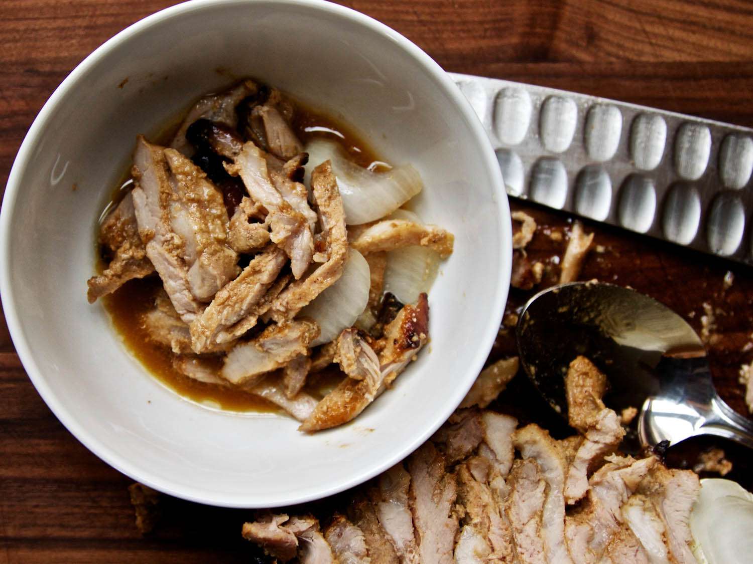 Overhead view of the sliced shawarma meat in a bowl, swimming in pan juices.