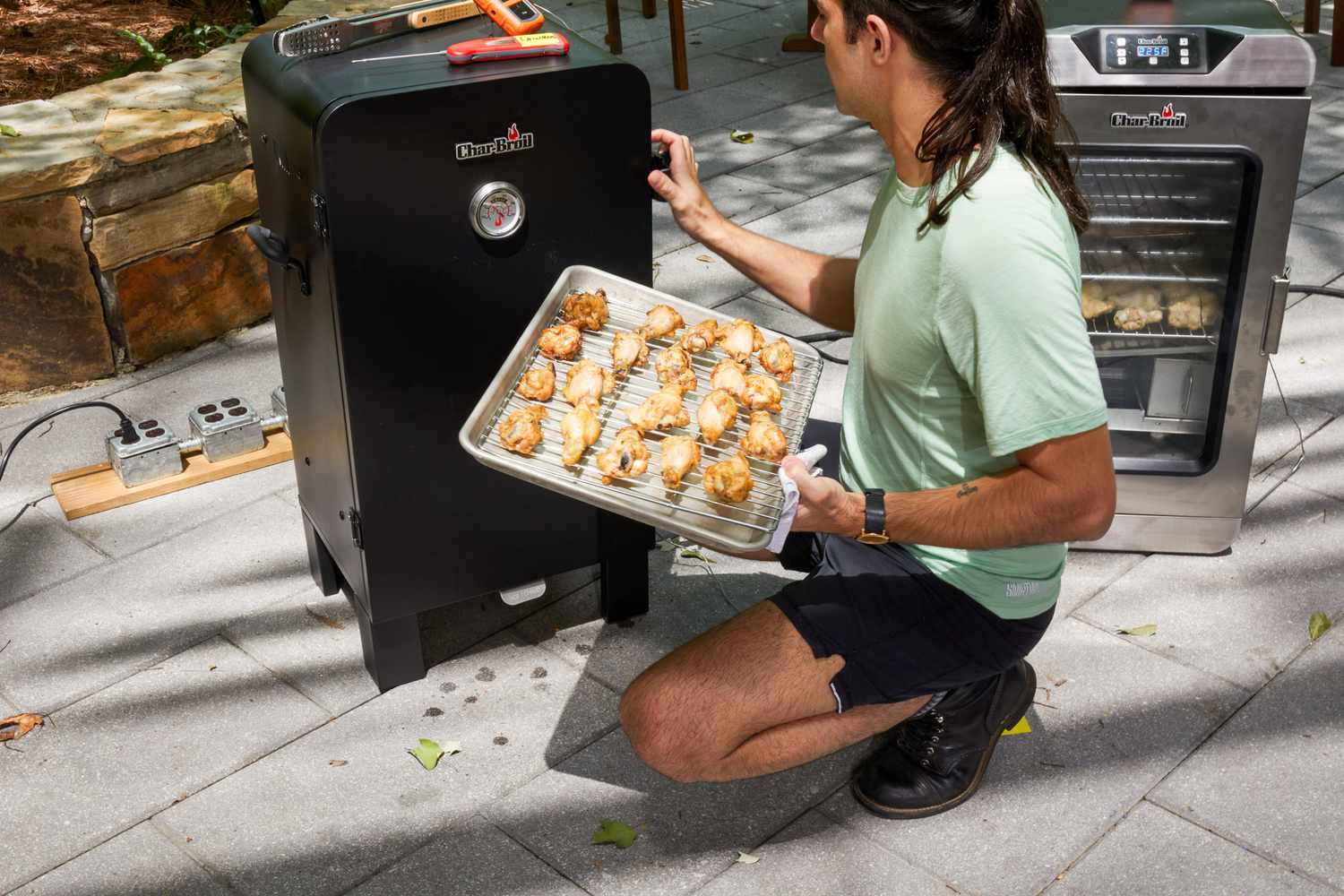 A person places chicken into the Char-Broil Analog Electric Smoker (18202077)