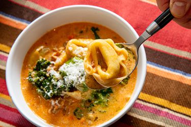 Overhead view of lifting up a spoon of tortellini from soup
