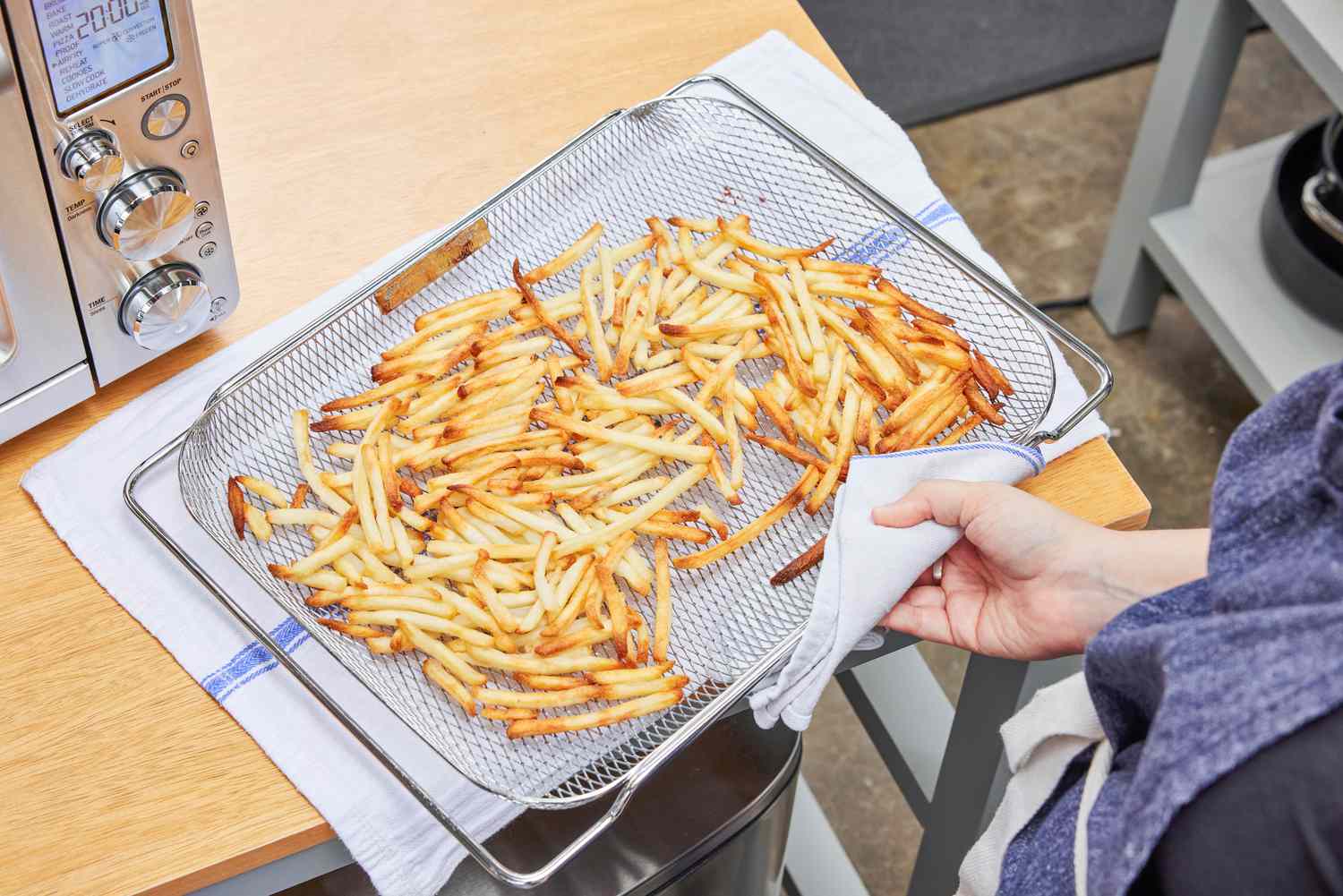 A hand holding a rack of fries that cooked in the Breville the Smart Oven Air Fryer