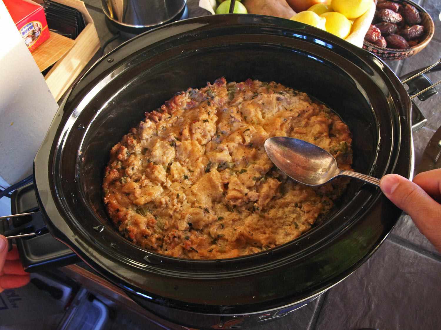 A spoon tapping on the crispy golden surface of stuffing made in a slow cooker. 