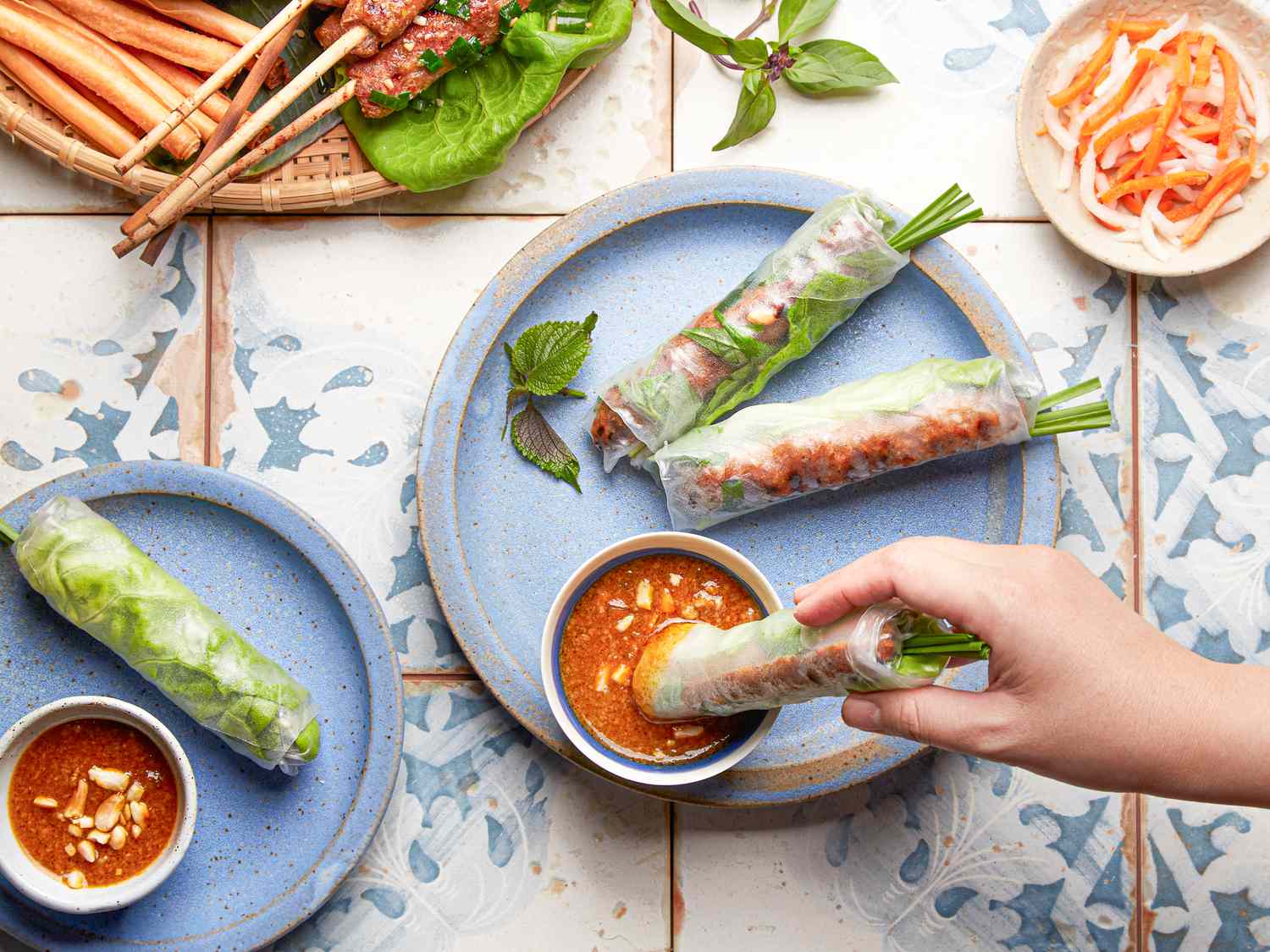 Overhead view of hands dipping rolls into peanut sauce 