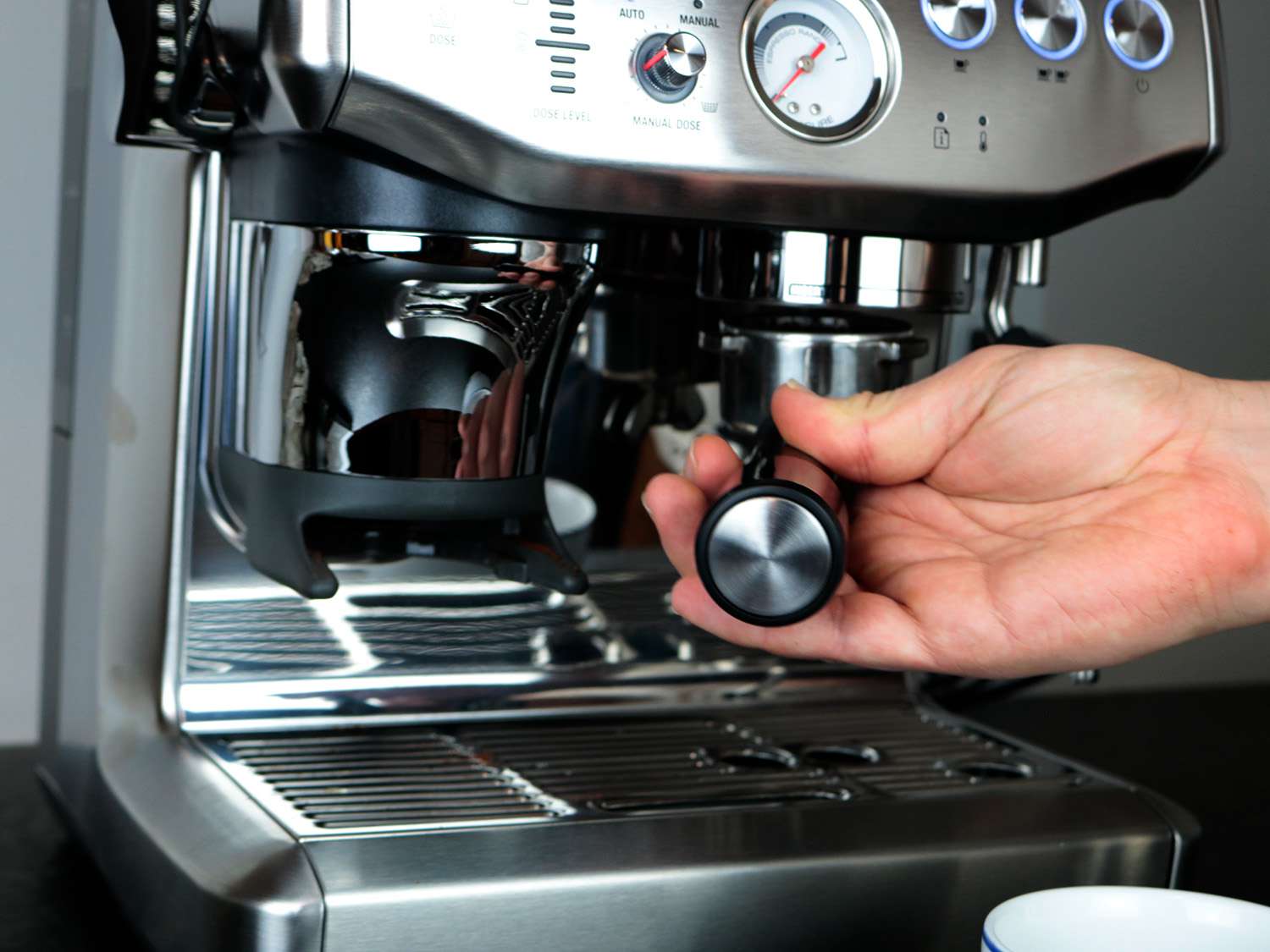 a hand inserts a portafilter into an espresso machine 