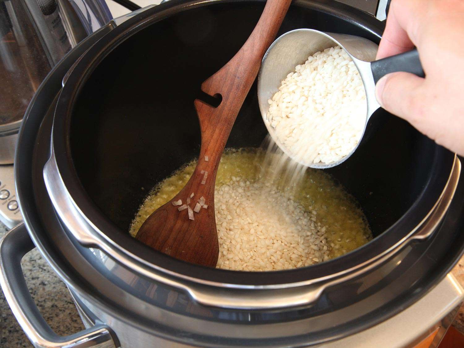 Adding rice to toast in oil in a pressure cooker. 