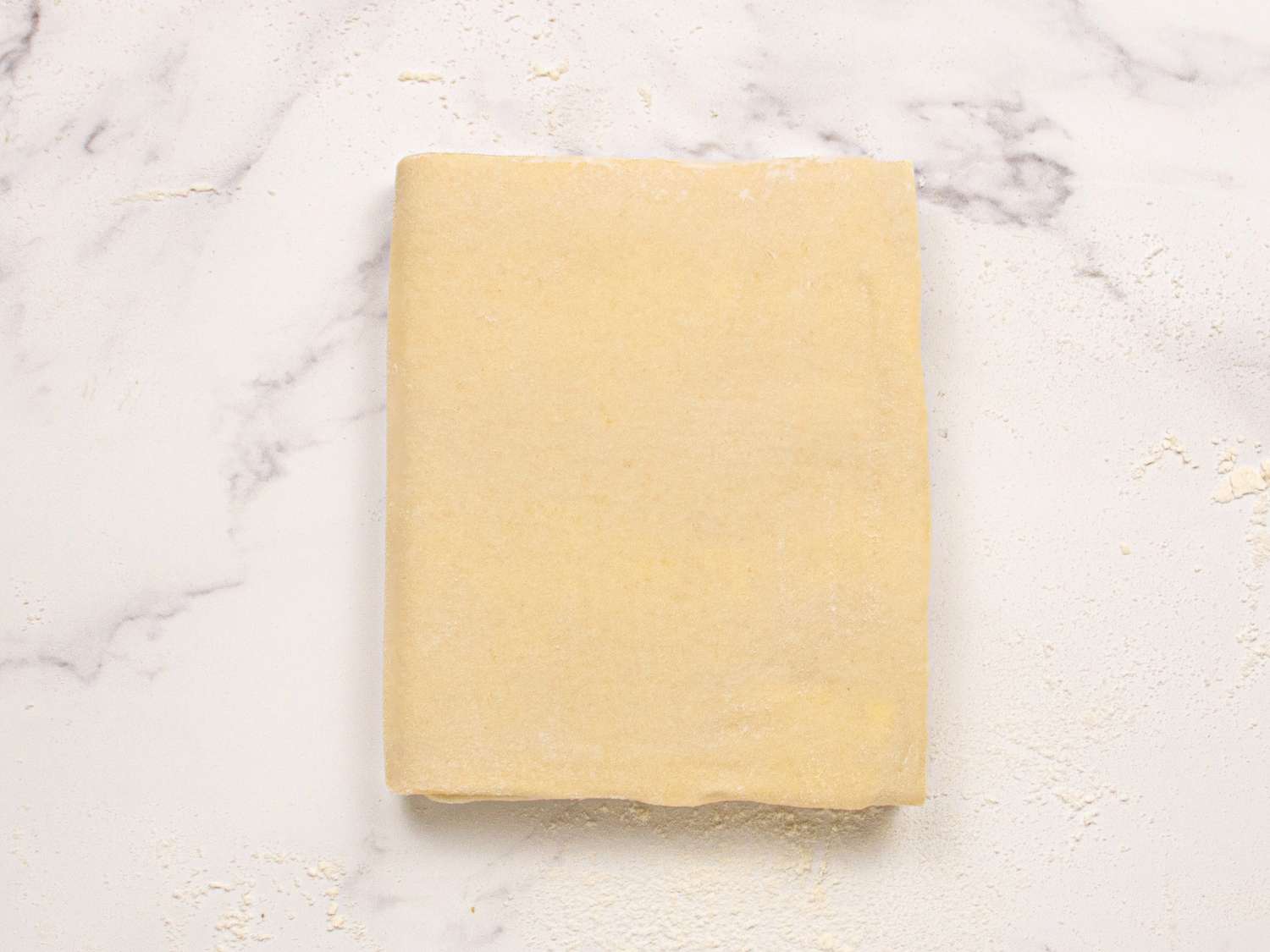 Folded pastry dough on a floured surface prepared for making croissants