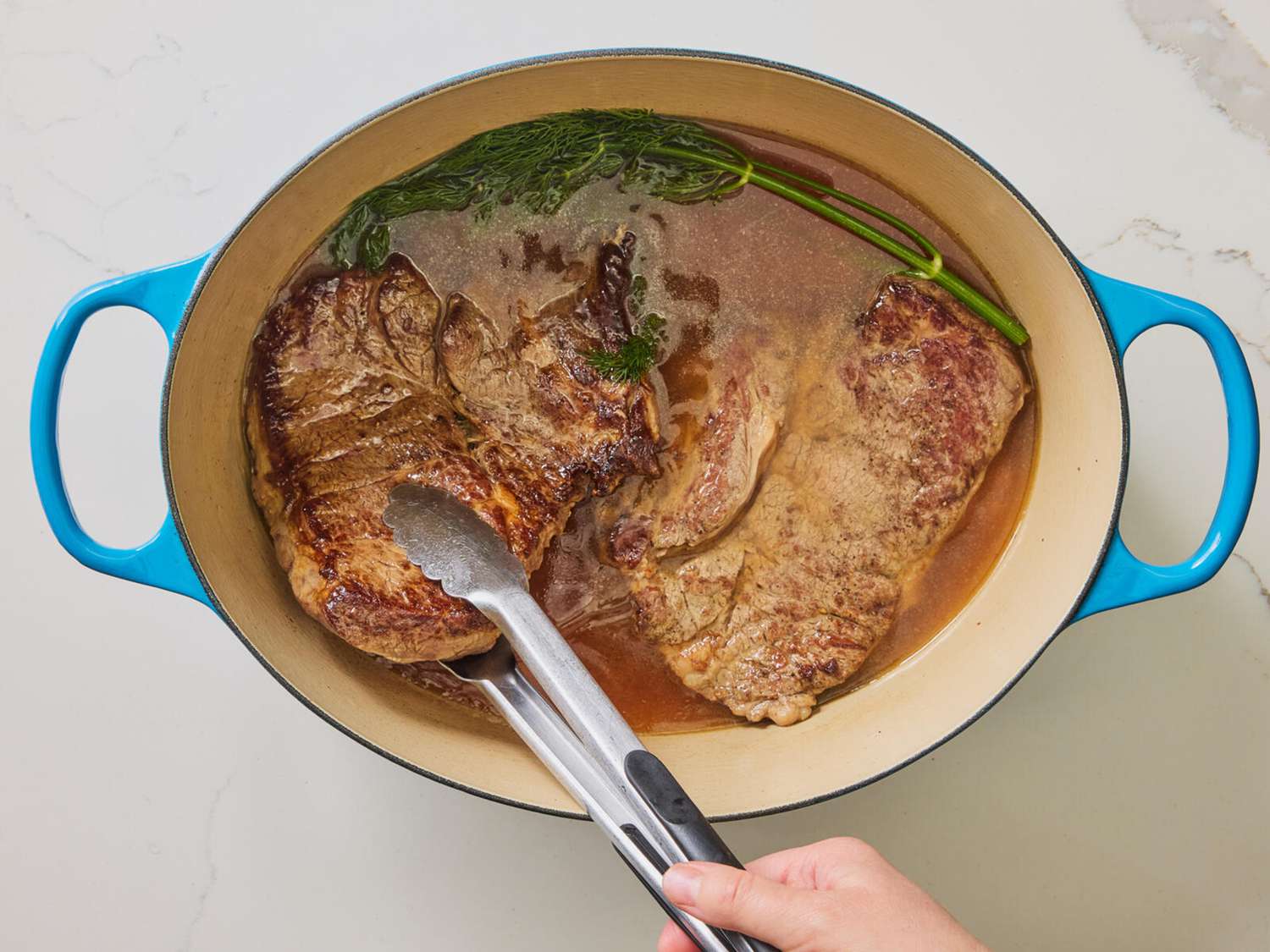 Chuck roast added to dutch oven with dill and broth