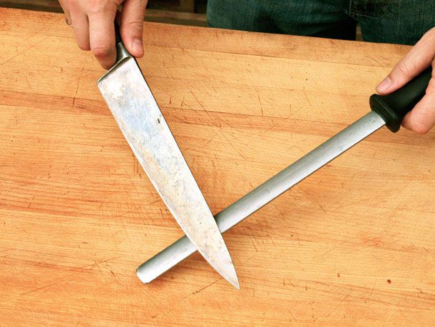 A chef's knife being honed with a diamond steel.