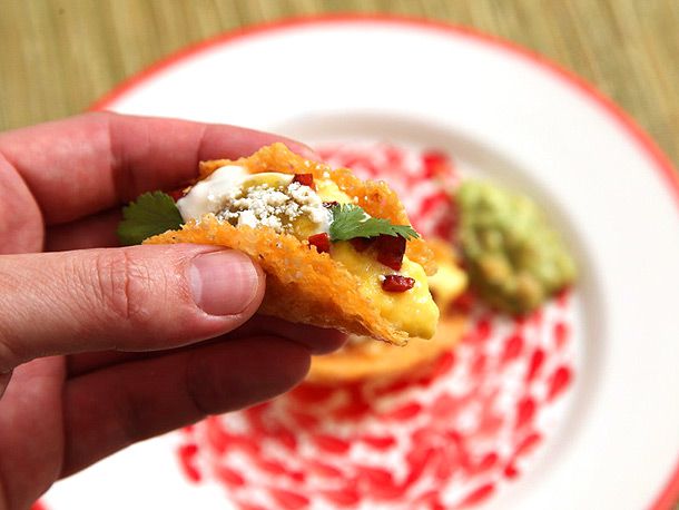 A hand hold a mini crispy all-cheese breakfast taco.